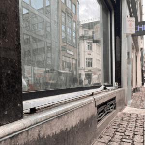 Fenstersims eines Geschäfts mit aufgesetzter Metallleiste.